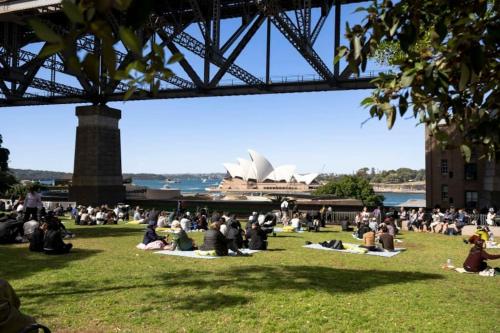 a crowd of people sitting on the grass under a bridge at Holiday Home by Barangaroo Reserve in Sydney