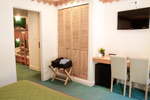 a room with a desk and a table and a television at Hôtel Le Bois Joli in Cauterets