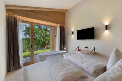 a white bed in a room with a window at Oberplunerhof Luxury Chalet Woods in Colli in Pusteria