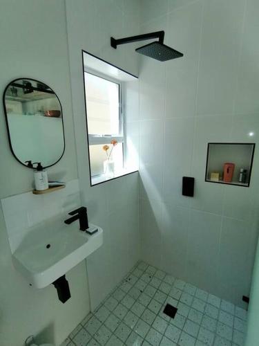 a white bathroom with a sink and a mirror at Melkbos Sea Spray Studio Apartment in Cape Town