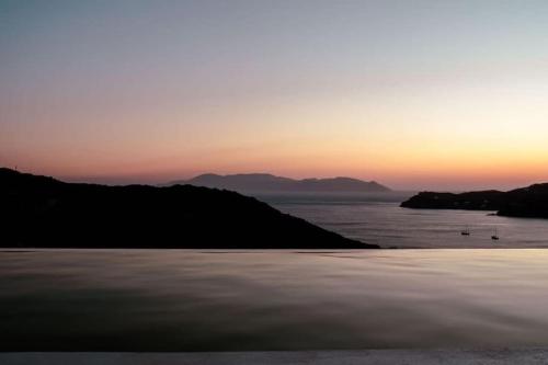 a sunset over the water with mountains in the background at Thalassa in Ios Chora