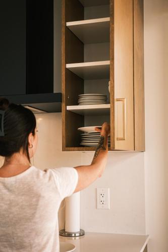 a woman is unlocking a cupboard in a kitchen at Hôtel Expérience - Quartier Des Marinas in Magog-Orford