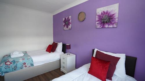 a bedroom with two beds and a clock on the wall at 59A Comfortable 3 Bedroom Home, Sleeps 6 By Easy 2 Manage in Cranford