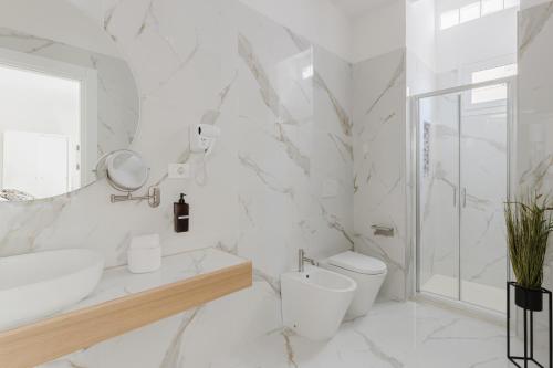 a white bathroom with a toilet and a sink at New Elegance Suites Guesthouse in Oristano