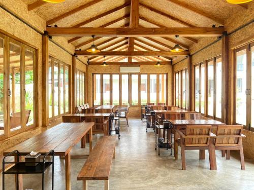 a room with wooden tables and chairs and windows at น่าน ม่วนใจ Nan Muanjai Hotel in Pua