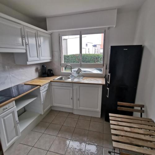 une cuisine avec des armoires blanches et un réfrigérateur noir dans l'établissement Chambre confort Saint Marceau, à Orléans