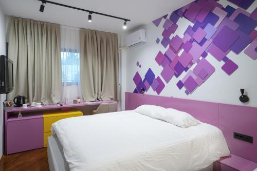 a bedroom with a white bed and a purple wall at 7even weddings & events in Štip