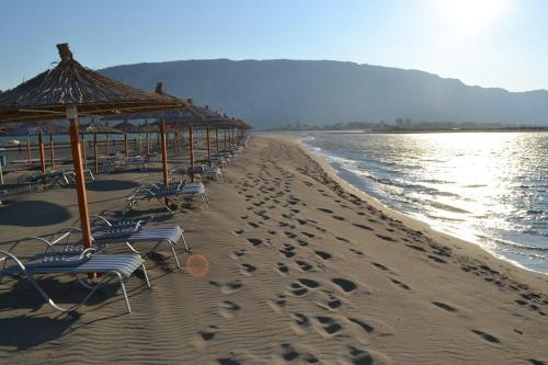 a row of chairs and umbrellas on a beach at Grand Hotel Europa Resort Velipoje Apartment in Velipojë