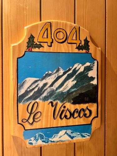a sign on a wooden wall with a snow covered mountain at Hôtel Le Bois Joli in Cauterets