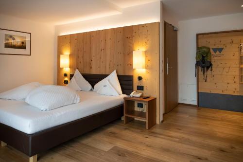 1 dormitorio con 1 cama con pared de madera en Artnatur Dolomites Hotel & Spa en Siusi