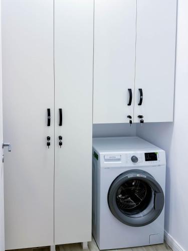 a washing machine in a laundry room with white cabinets at ACM Premium 3 camere Apartament elegant in Voluntari