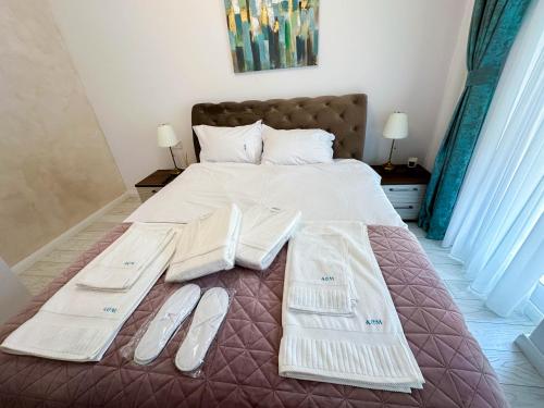 a bed with white towels and slippers on it at ACM Premium 3 camere Apartament elegant in Voluntari