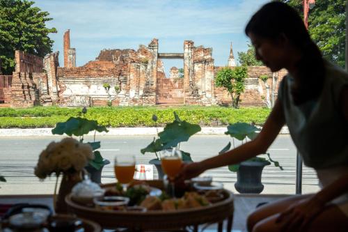 a woman standing in front of a table with food at One Dhatu Ayutthaya Premium Homestay in Phra Nakhon Si Ayutthaya