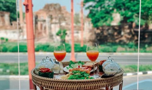 a table with two wine glasses and food on it at One Dhatu Ayutthaya Premium Homestay in Phra Nakhon Si Ayutthaya