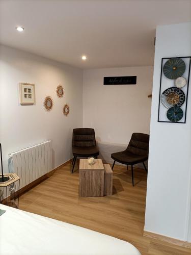 a room with two chairs and a table and a bed at Le Temps d'un Instant in Vattetot-sur-Mer