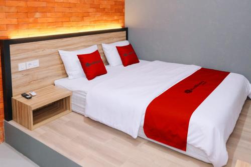 a bedroom with a large bed with red pillows at RedDoorz near Alun Alun Kembangjoyo Pati in Pati