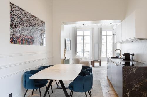 - une cuisine blanche avec une table et des chaises bleues dans l'établissement Pick A Flat's Apartment in Louvre - Croix des Petits Champs, à Paris
