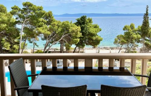a table and chairs on a balcony overlooking the ocean at Vila Vera Seafront Apartments in Sumartin