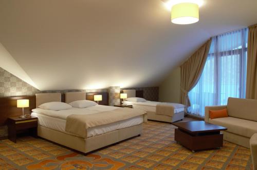 Hotel Via Baltica في وومجا: غرفة فندقية بسريرين واريكة