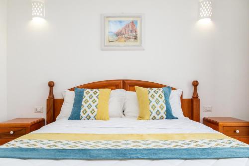 a bedroom with a bed with blue and yellow pillows at Hotel Vecchia Marina in Àrbatax