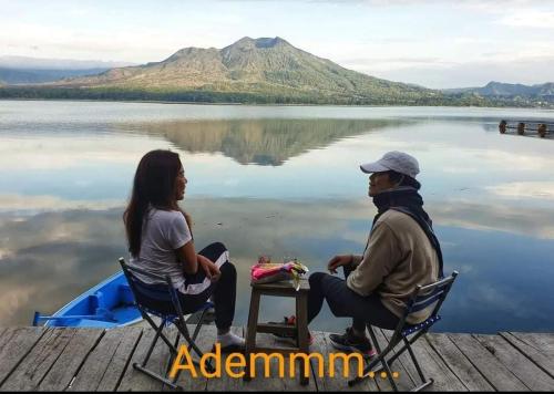 a man and a woman sitting on a dock near a lake at EMaYan Glamping in Kubupenlokan
