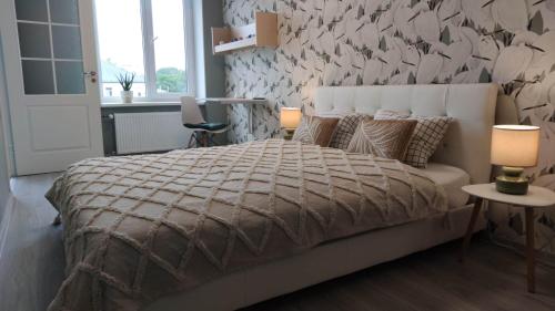 a bedroom with a large bed and a wall with flowers at Promenade Apartment in Liepāja