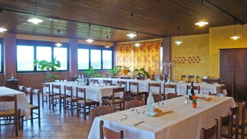 una sala da pranzo con tavoli e sedie bianchi e finestre di Il Girasole a Mombaruzzo