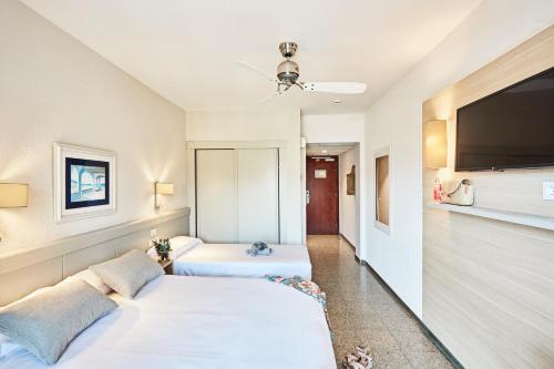 a bedroom with two beds and a flat screen tv at Prestige Goya Park in Roses