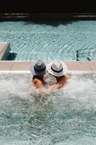two people wearing hats in a swimming pool at DAS RONACHER Thermal Spa Hotel in Bad Kleinkirchheim