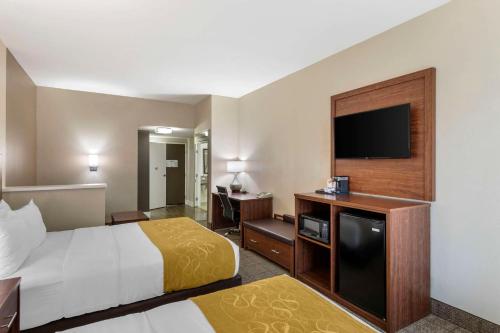 a hotel room with a bed and a flat screen tv at Comfort Suites in Tulare