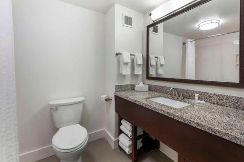 a bathroom with a toilet and a sink and a mirror at Comfort Suites in Tulare