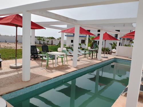 a pool with tables and chairs and umbrellas at Riad Sahara Sunset Beach Douira Agadir in Douaïra