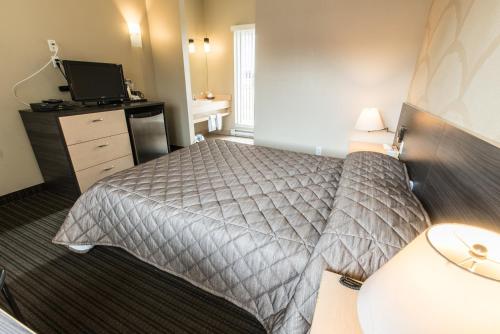 a hotel room with a bed and a television at Motel Falcon in Brossard