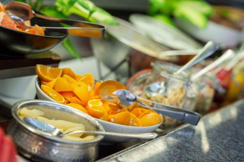 a buffet with bowls of fruit and utensils at Rydges Esplanade Resort Cairns in Cairns