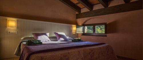 Un dormitorio con una cama con sábanas moradas y una ventana en Les Quimeres, en Falset