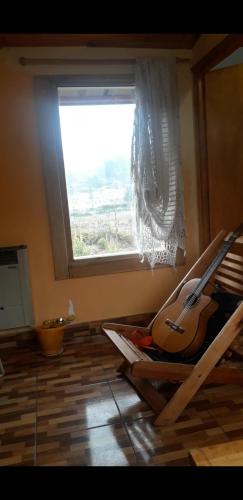 a room with a window and a guitar laying on the floor at Cabaña Renacer in Golondrinas