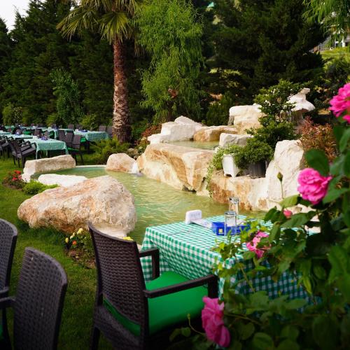 a table and chairs next to a pond with a fountain at Titanic Hotel & SPA in As Sulaymānīyah