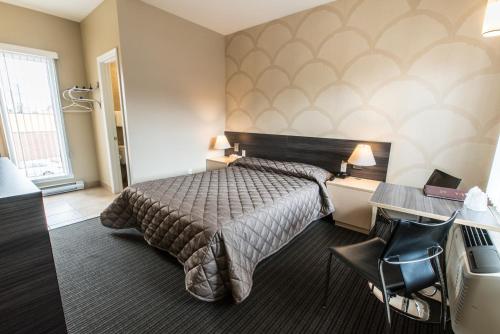 a hotel room with a bed and a desk at Motel Falcon in Brossard
