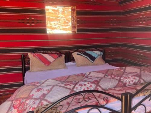 a bed in a room with a red wall at Wadi Rum Desert Adventures in Wadi Rum