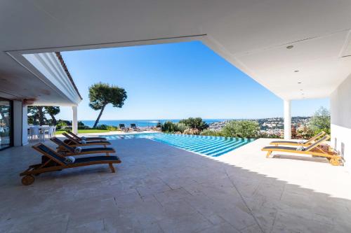 une piscine avec des chaises longues et l'océan dans l'établissement VILLA ADRIANA VI4411 By Riviera Holiday Homes, à Nice