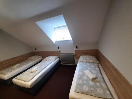 three beds in a room with a skylight at Hotel Boršičanka in Havířov