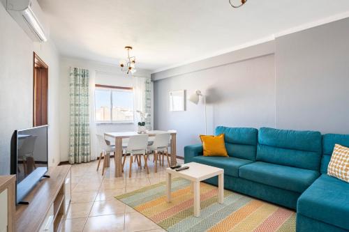 a living room with a blue couch and a table at Apartamentos Casal Ventoso in Pedrógão