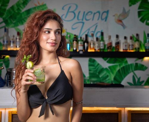 a woman in a bikini holding a drink in a bar at Buena Vida Beach Resort in Morjim