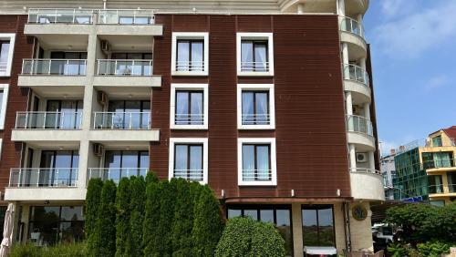 a red brick building with a tree in front of it at Stamopolulux директен изглед към морето in Primorsko