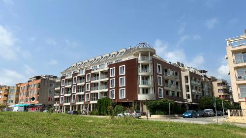 a large brick building with cars parked in a parking lot at Stamopolulux директен изглед към морето in Primorsko