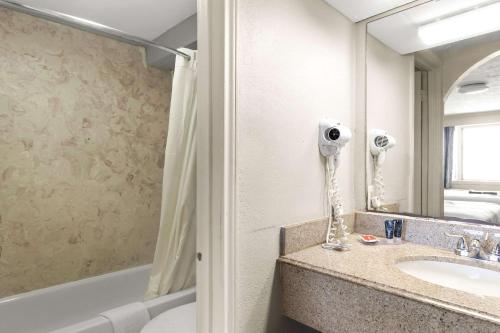 a bathroom with a sink and a toilet and a mirror at Econo Lodge Galveston Seawall in Galveston