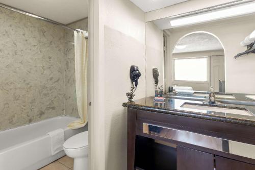 a bathroom with a sink and a toilet and a phone at Econo Lodge Galveston Seawall in Galveston