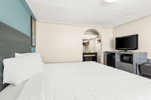 a bedroom with a white bed and a flat screen tv at Econo Lodge Galveston Seawall in Galveston