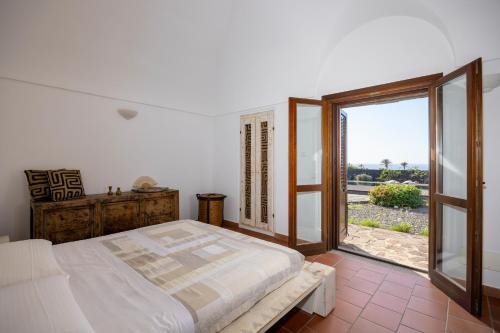 a bedroom with a bed and a large window at Dammuso Luna - Piscina Privata con Vista Mare in Pantelleria