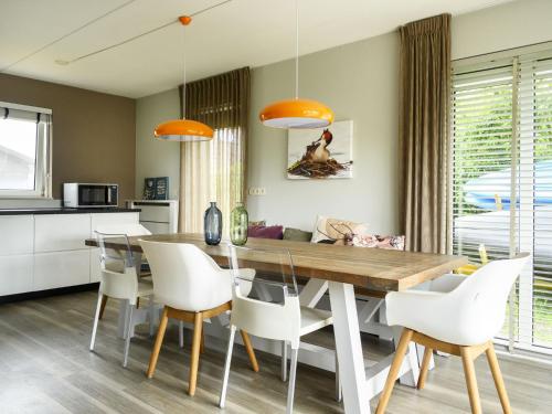 a kitchen and dining room with a wooden table and white chairs at Holiday Home Bungalowpark It Wiid by Interhome in Eernewoude